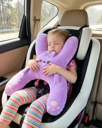 A toddler girl asleep in a car seat hugging Nina the Bunny