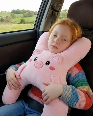 A girl on the back seat hugging Ollie the Piggy, seat belt on