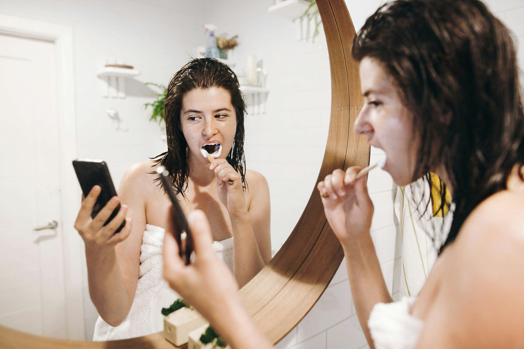 Person brushing teeth incorrectly while using phone, representing common brushing mistakes