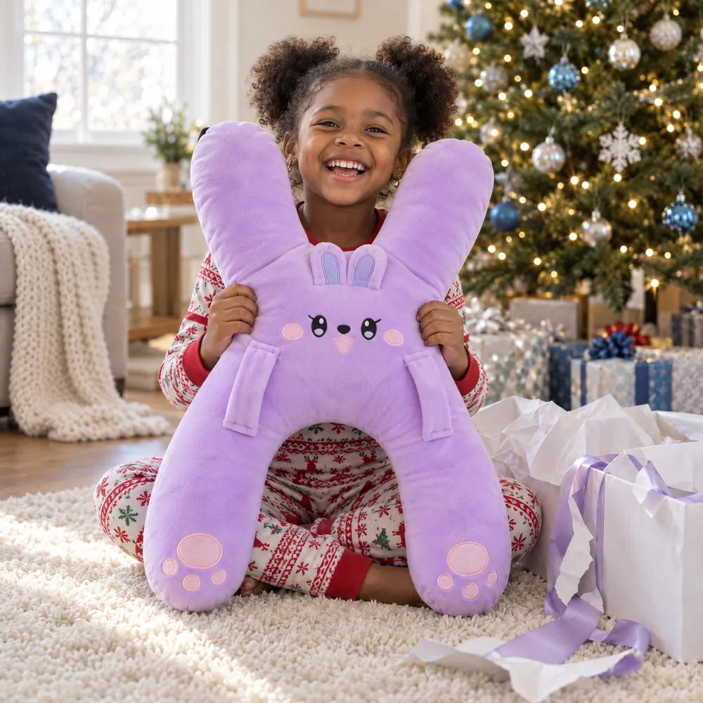 A girl by the holiday tree hugging Nina the Bunny she just unwrapped