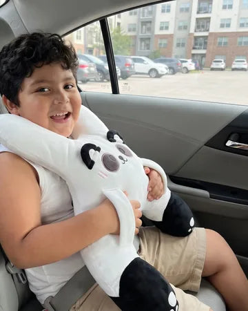 A boy on the back seat hugging Bao the Panda, seat belt on